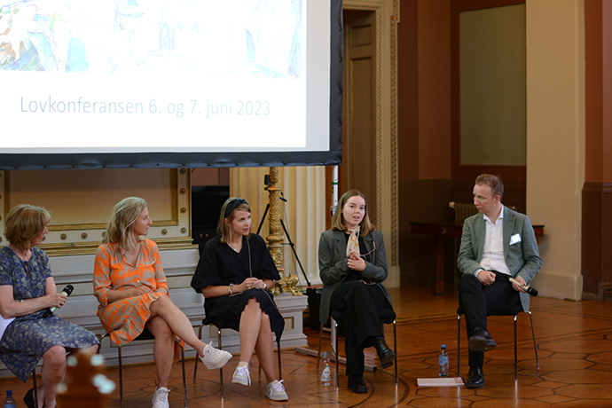 Fire kvinner og en mann sitter i et panel og diskuterer.