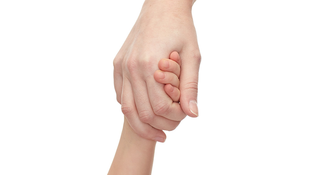 en voksenhånd og barnehånd holder hender.
