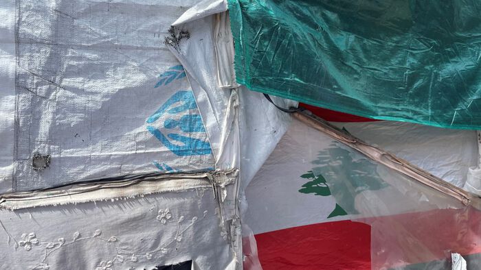 Tarpaulin of different textures, one with the UNHCR logo, another with the Lebanese flag. 