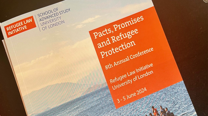 Close up of the conference programme which features a photograph of people tightly packed on a small boat in the ocean.
