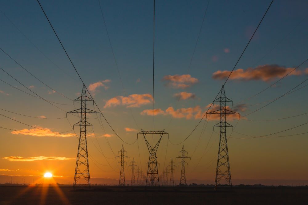 The image shows power pylons at sunset.
