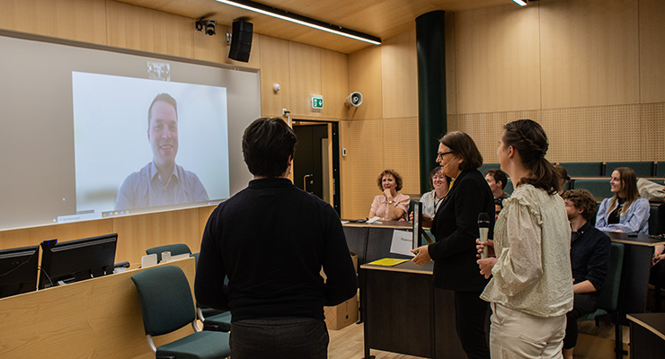 People in an auditorium communicating with a man digitally on a projector.