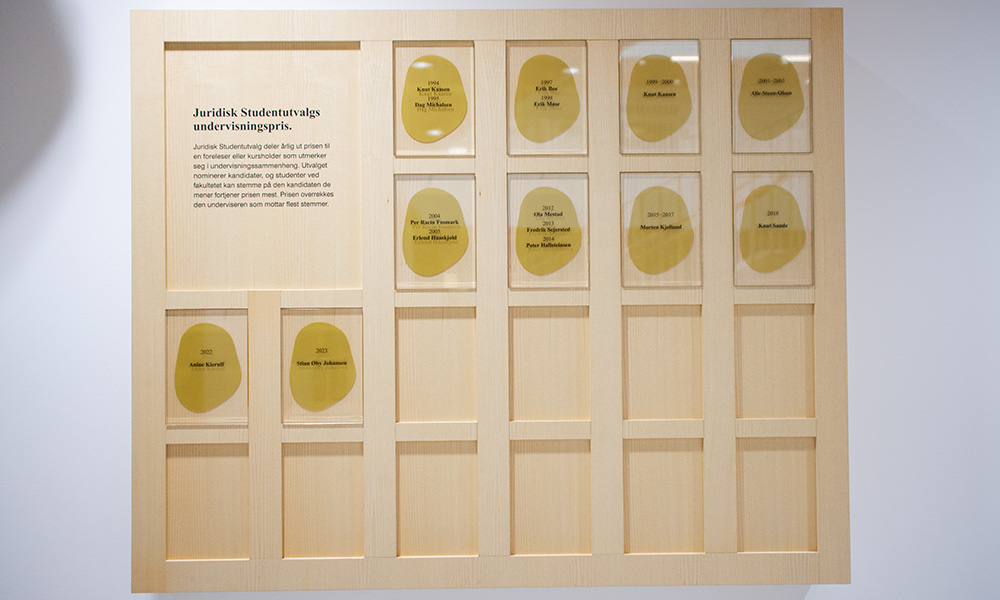 Photo of a picture frame with glass panels displaying the names of the winners of JSUs Undervisningspris.