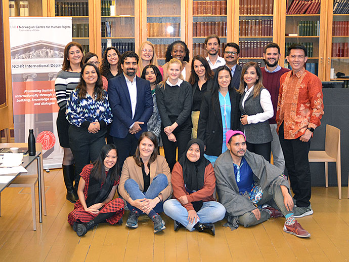 Group photo of all participants and NCHR representative in front of NCHR banner and library shelf